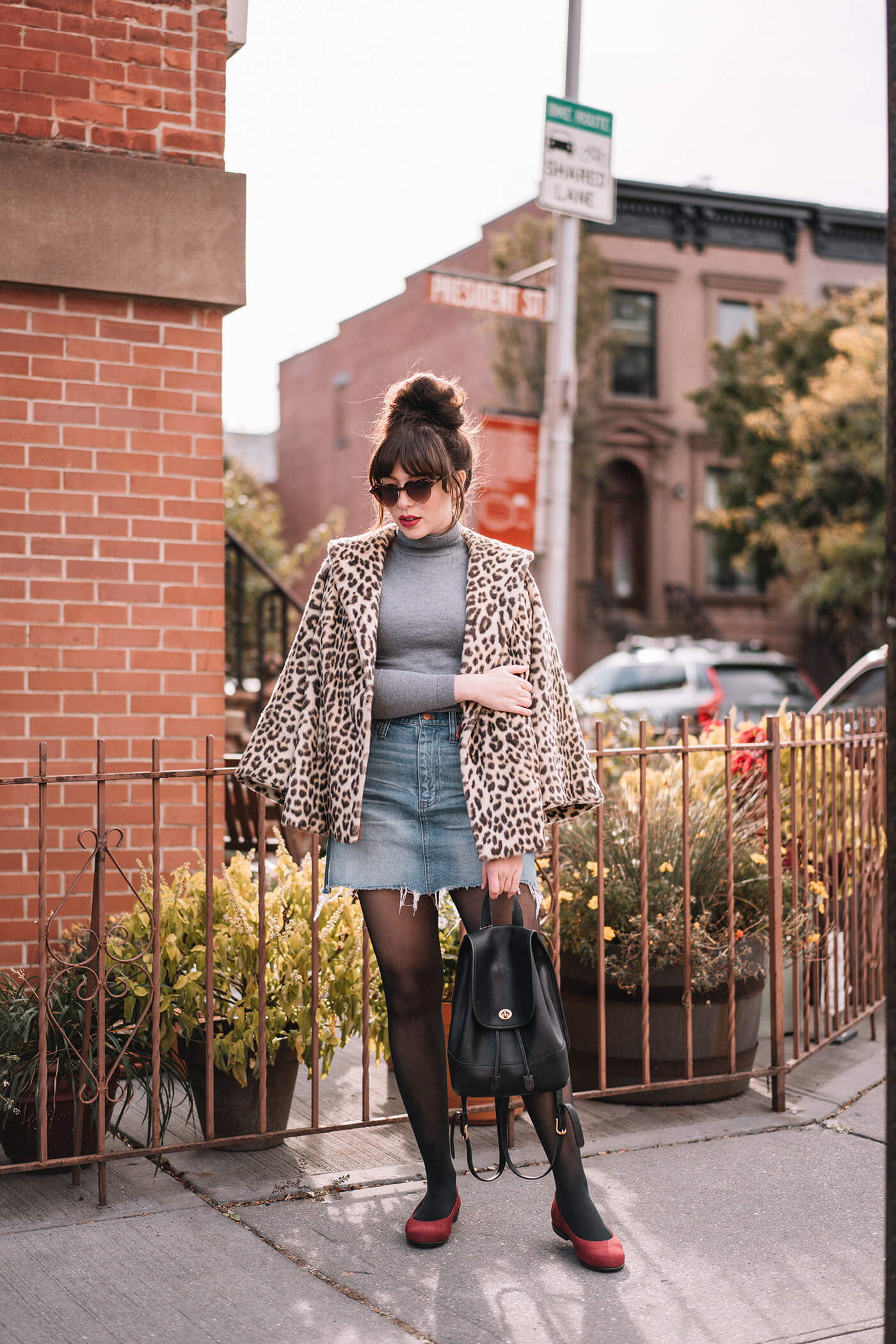 woman wearing vintage leopard coat, gray shirt, and denim skirt for fall outfit roundup