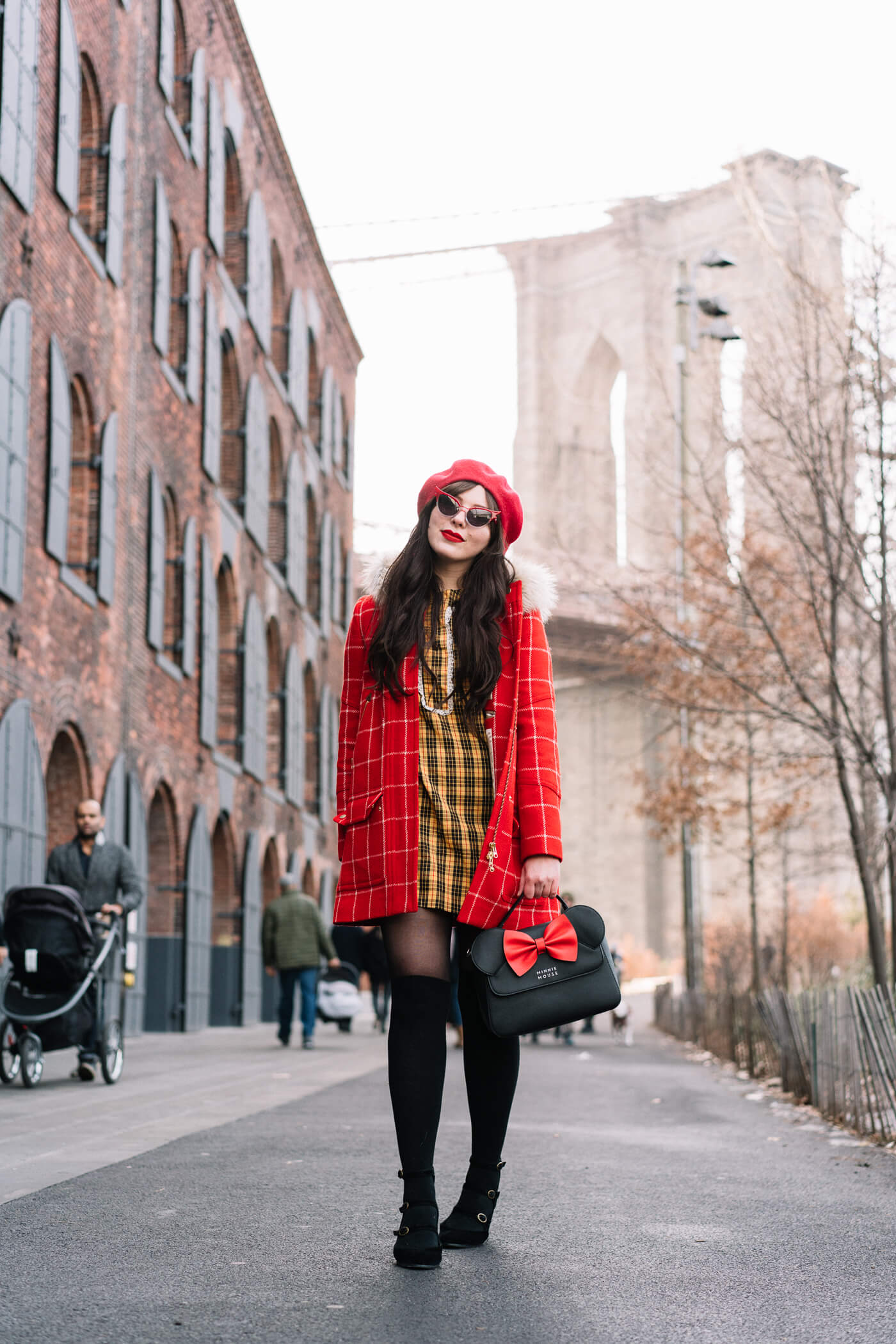 Keiko Lynn wearing a red checkered parka, vintage yellow plaid dress, red beret, minnie mouse bag, betty and veronica sunglasses, and black suede strappy block heels