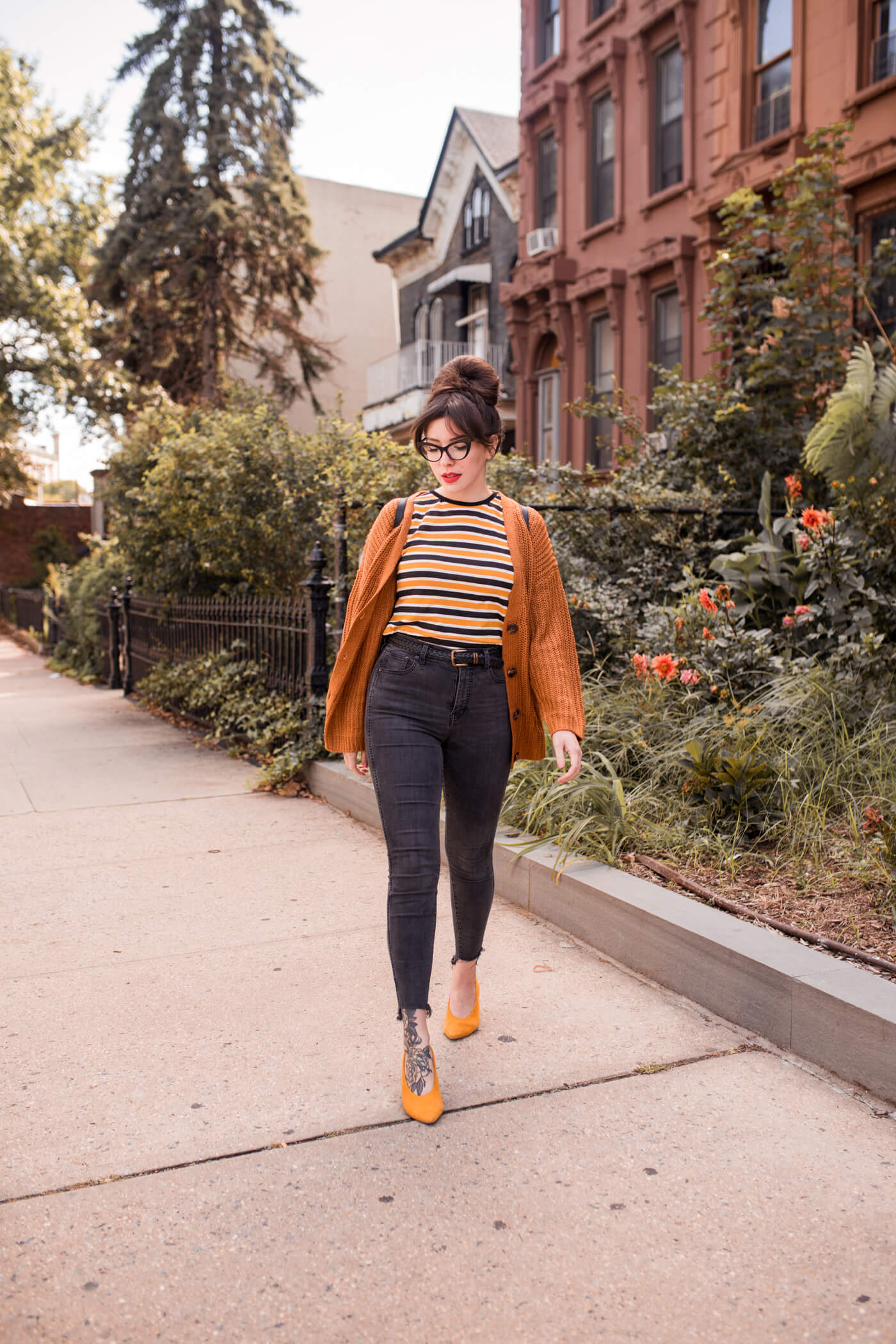 woman wearing orange sweater, strip shirt, and black jeans for fall outfit roundup