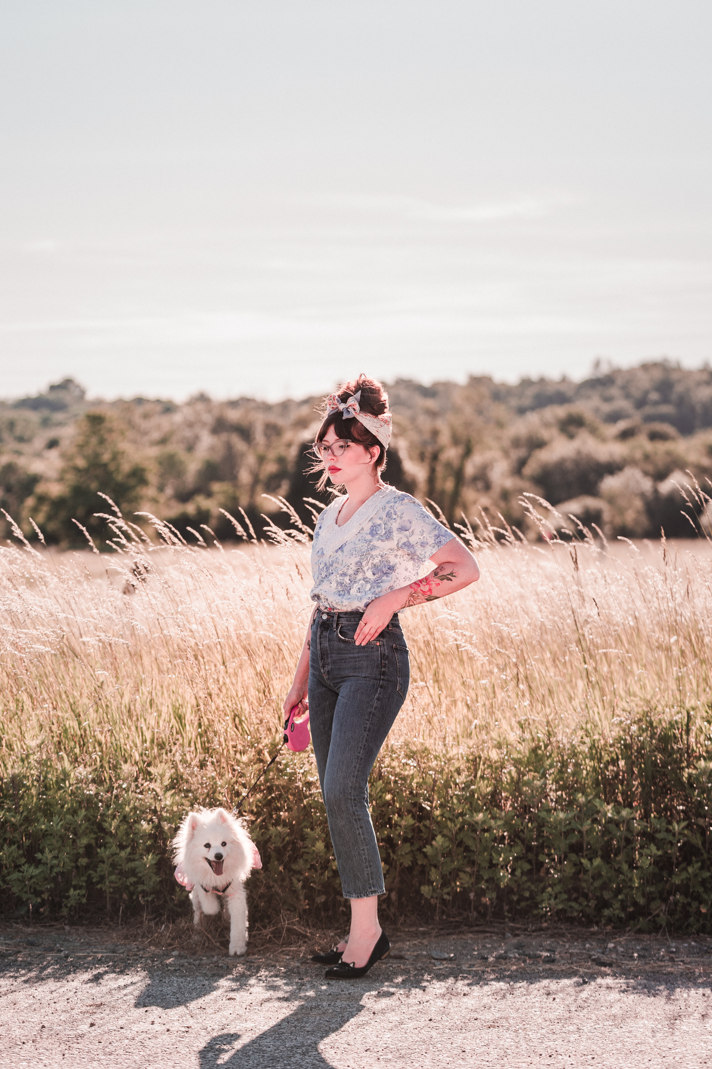 stylish woman standing beside a road with her dog sharing something new