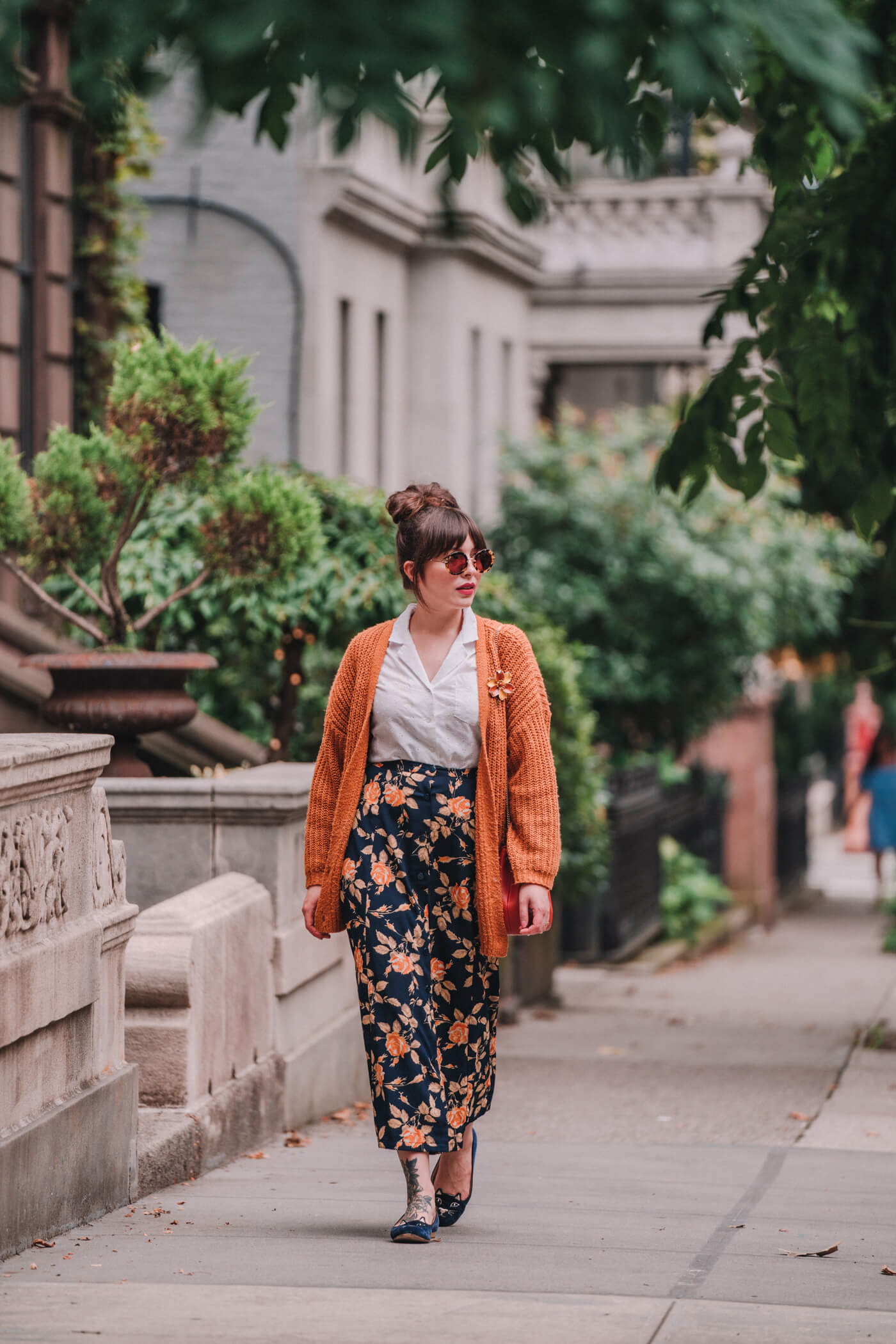 woman wearing white shirt, floral skirt, and orange sweater