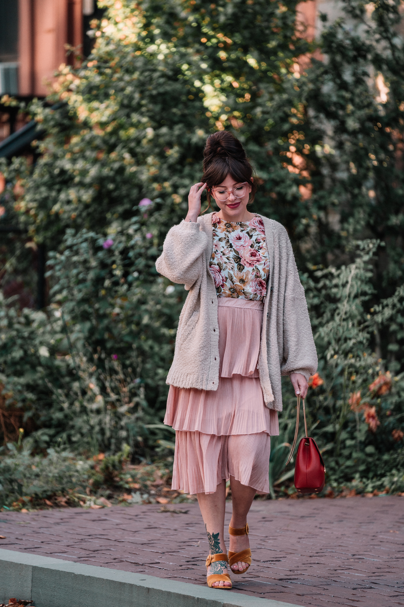woman wearing floral fall outfit with tiered blush skirt, cozy knit sweater, and velvet heels for Go forward with kindness
