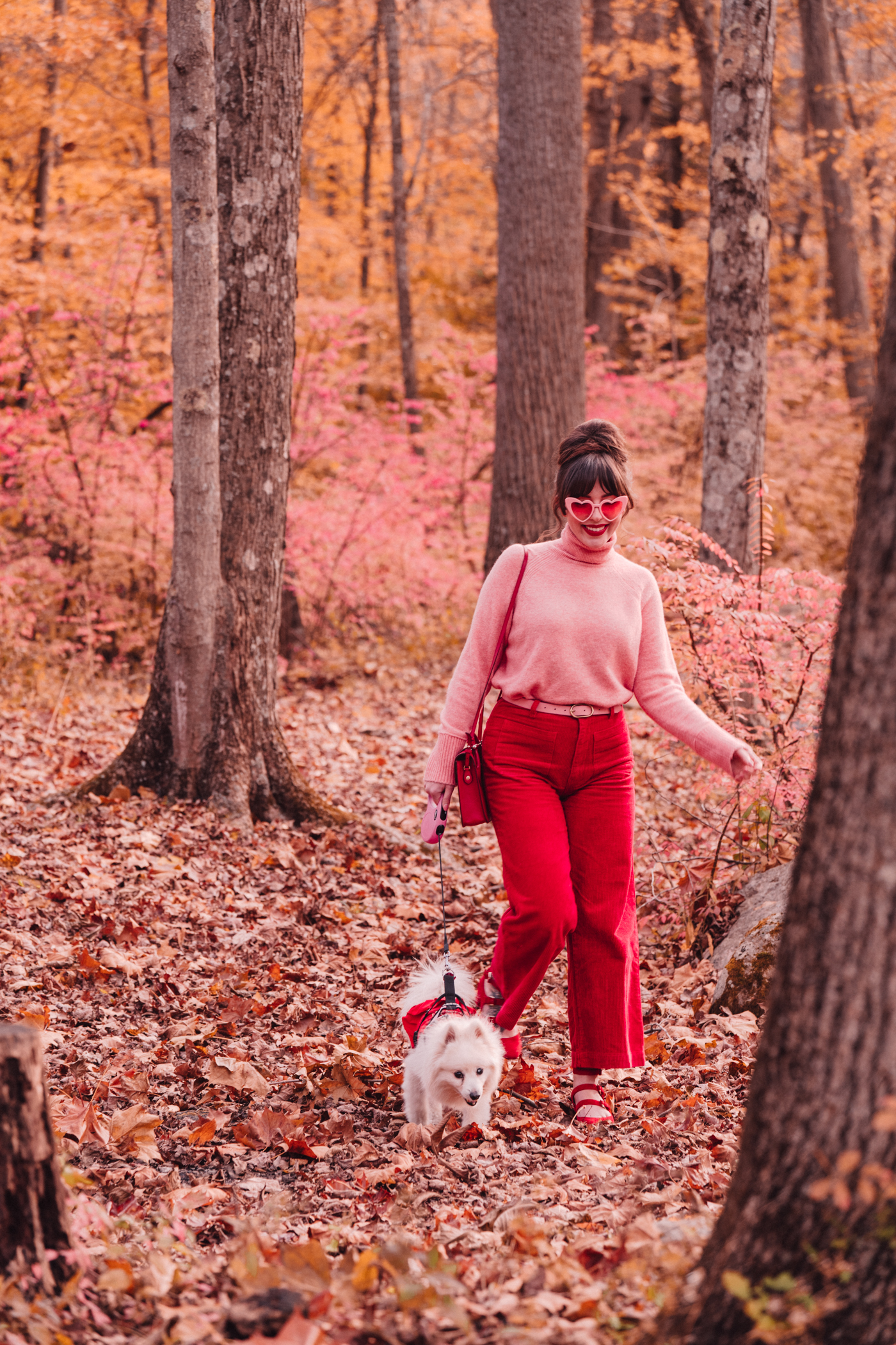 woman wearing pink and red top and pants in the outdoors with her dog