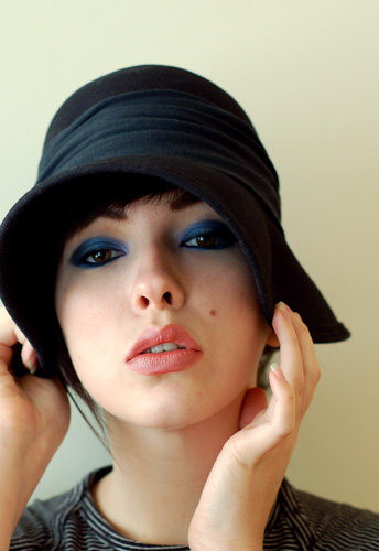 woman wearing blue signature eye makeup and a black cap