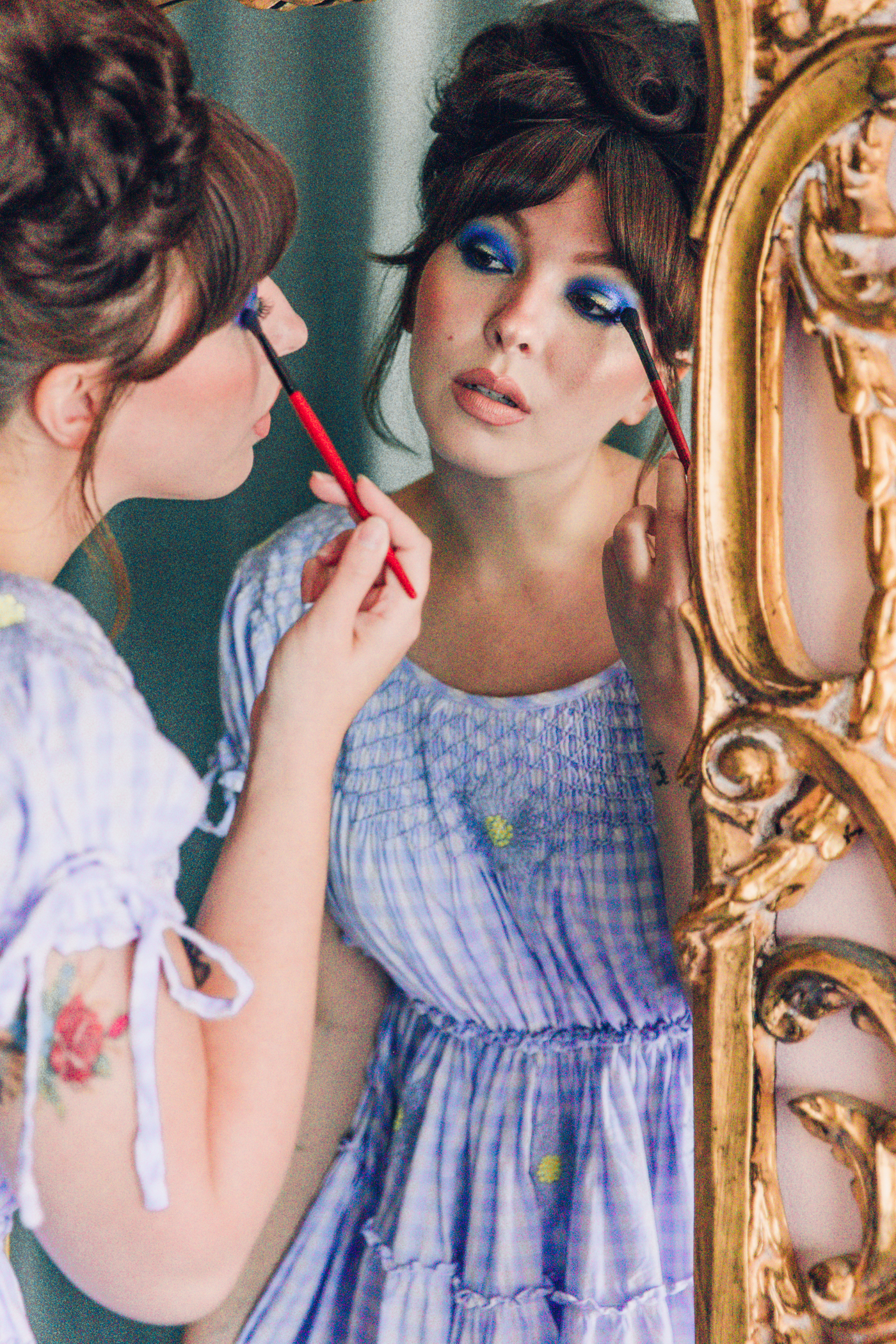 woman looking in the mirror and applying signature eye makeup