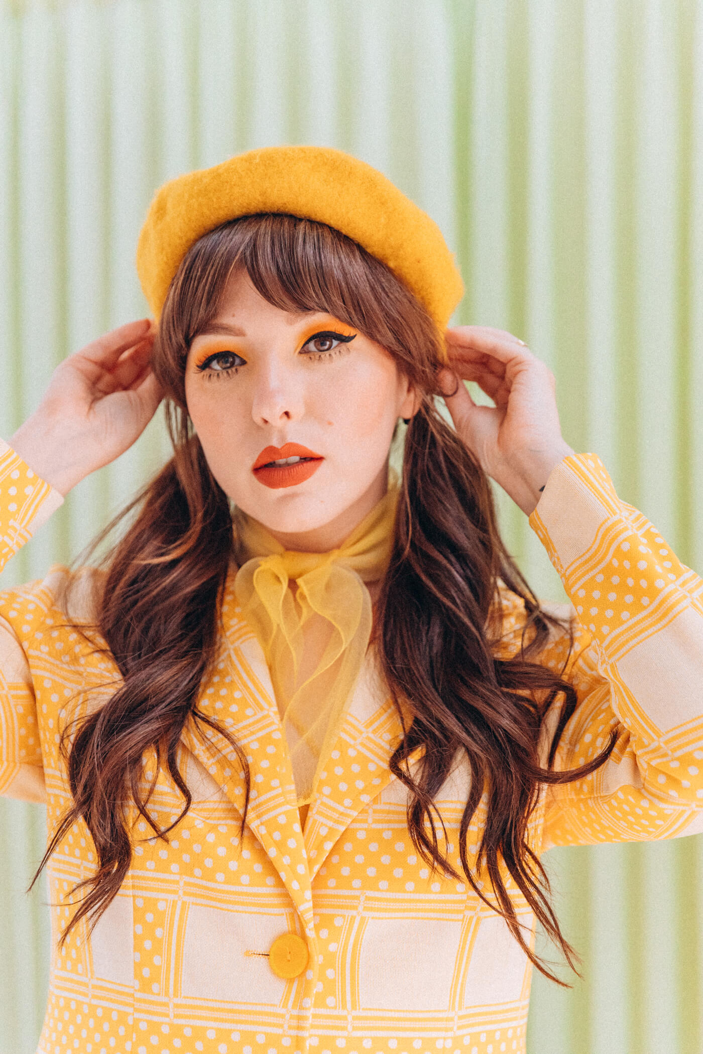 woman looking at the camera and has Fake Lower Lashes nd wearing yellow clothes