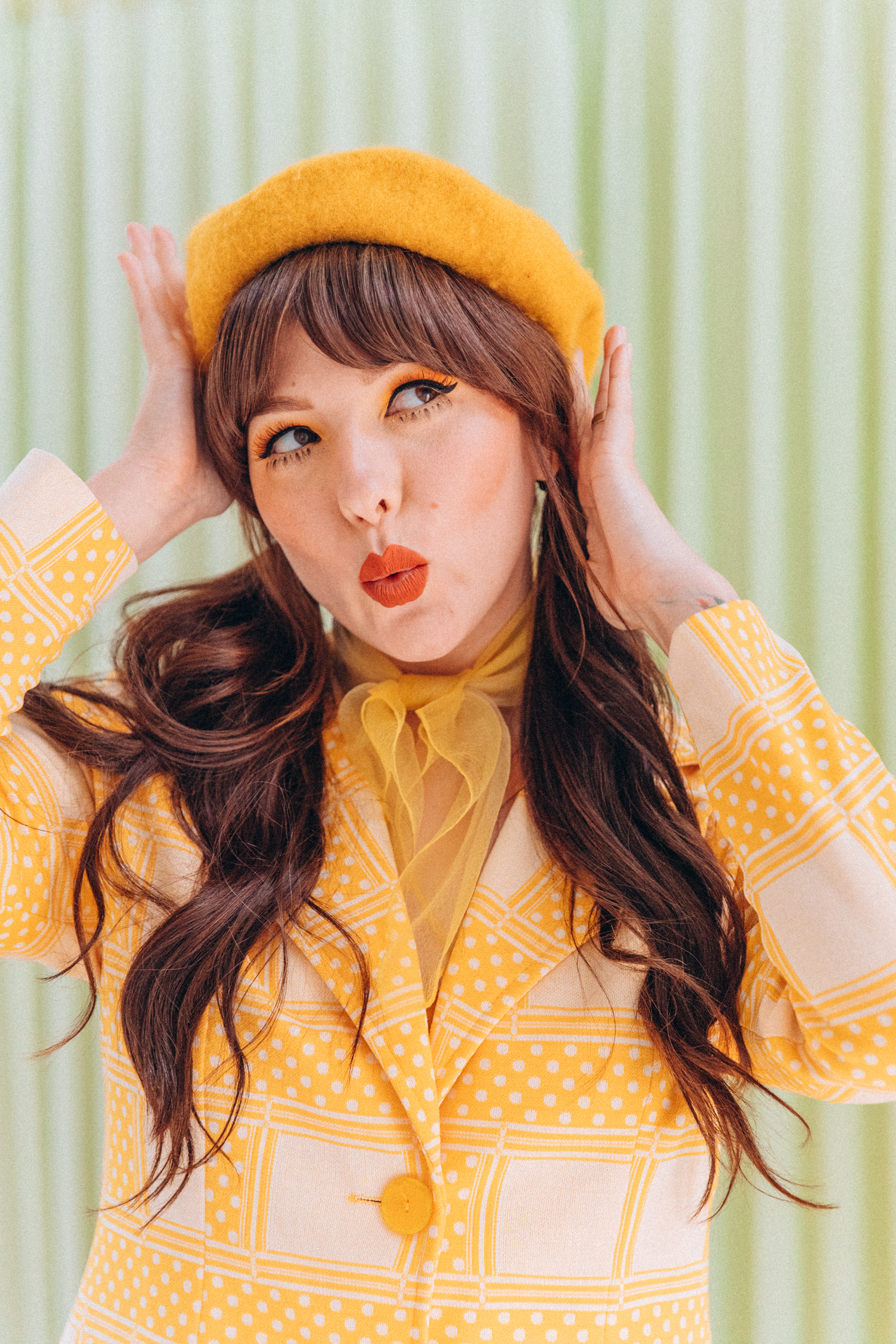 woman wearing yellow dress and hat with yellow signature eye makeup 
