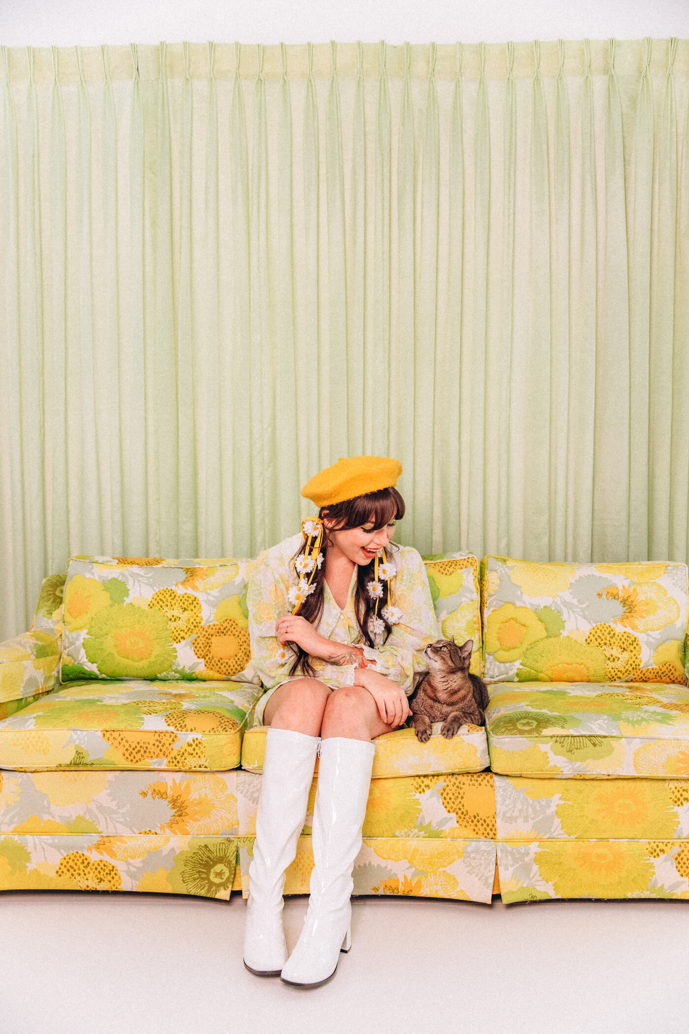 woman and a cat sitting on a yellow floral couch
