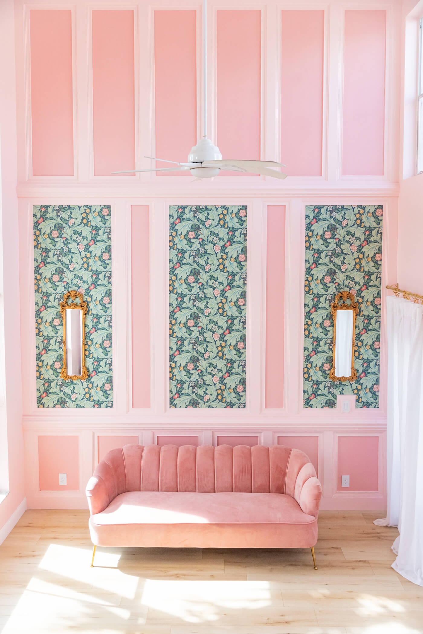 living room with pink velvet couch and floral green and pink walls 