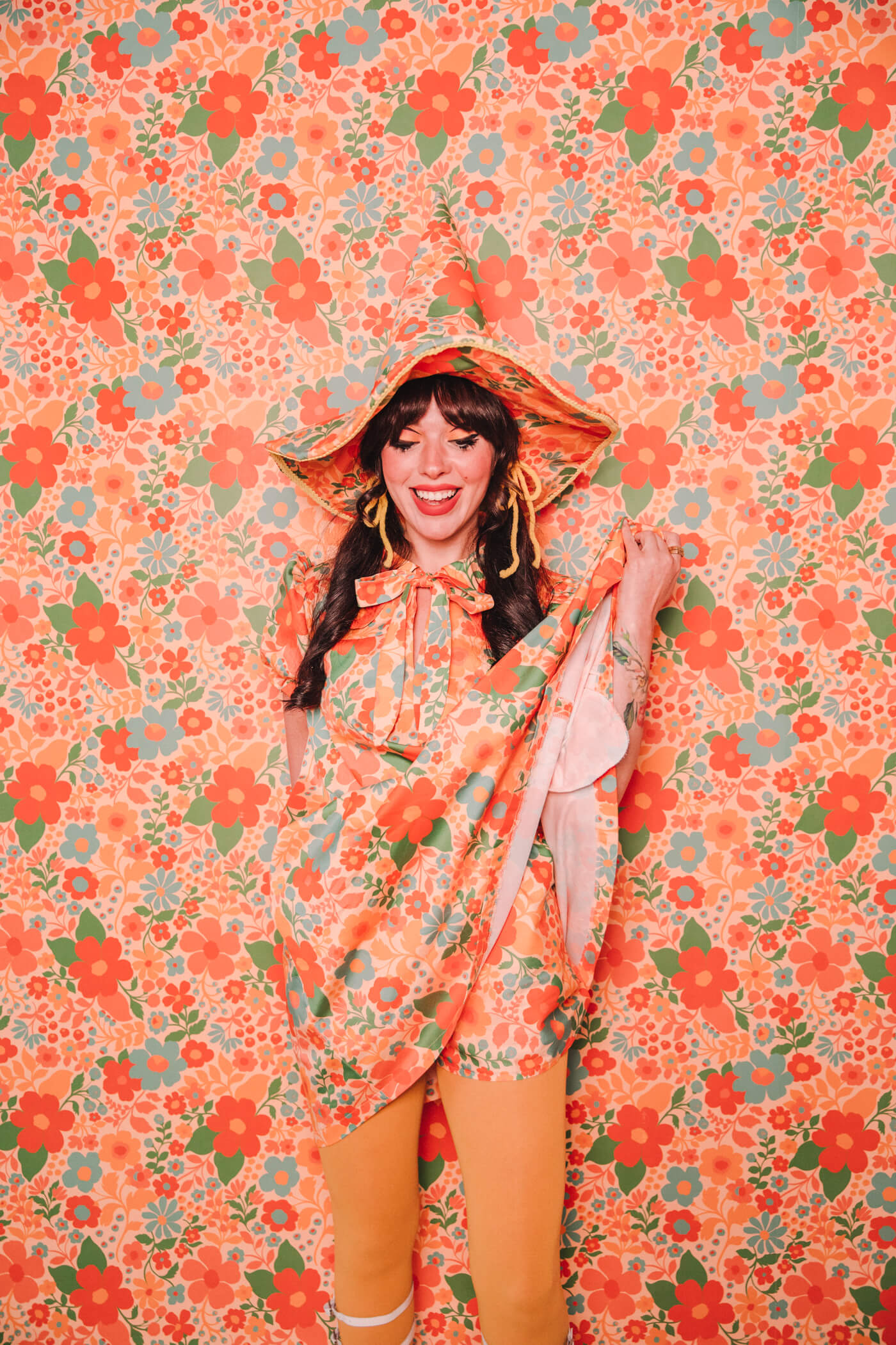 Keiko Lynn wearing a handmade dress and matching witch hat made out of Spoonflower fabric, in front of matching wallpaper in the same print.