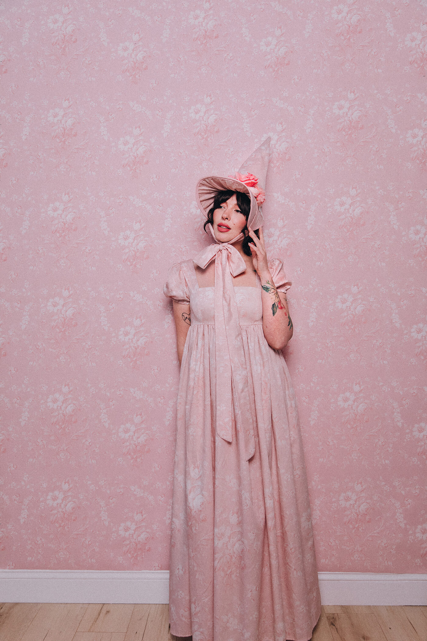 Keiko Lynn wearing a handmade dress and matching witch hat made out of Spoonflower fabric, in front of matching wallpaper in the same print.