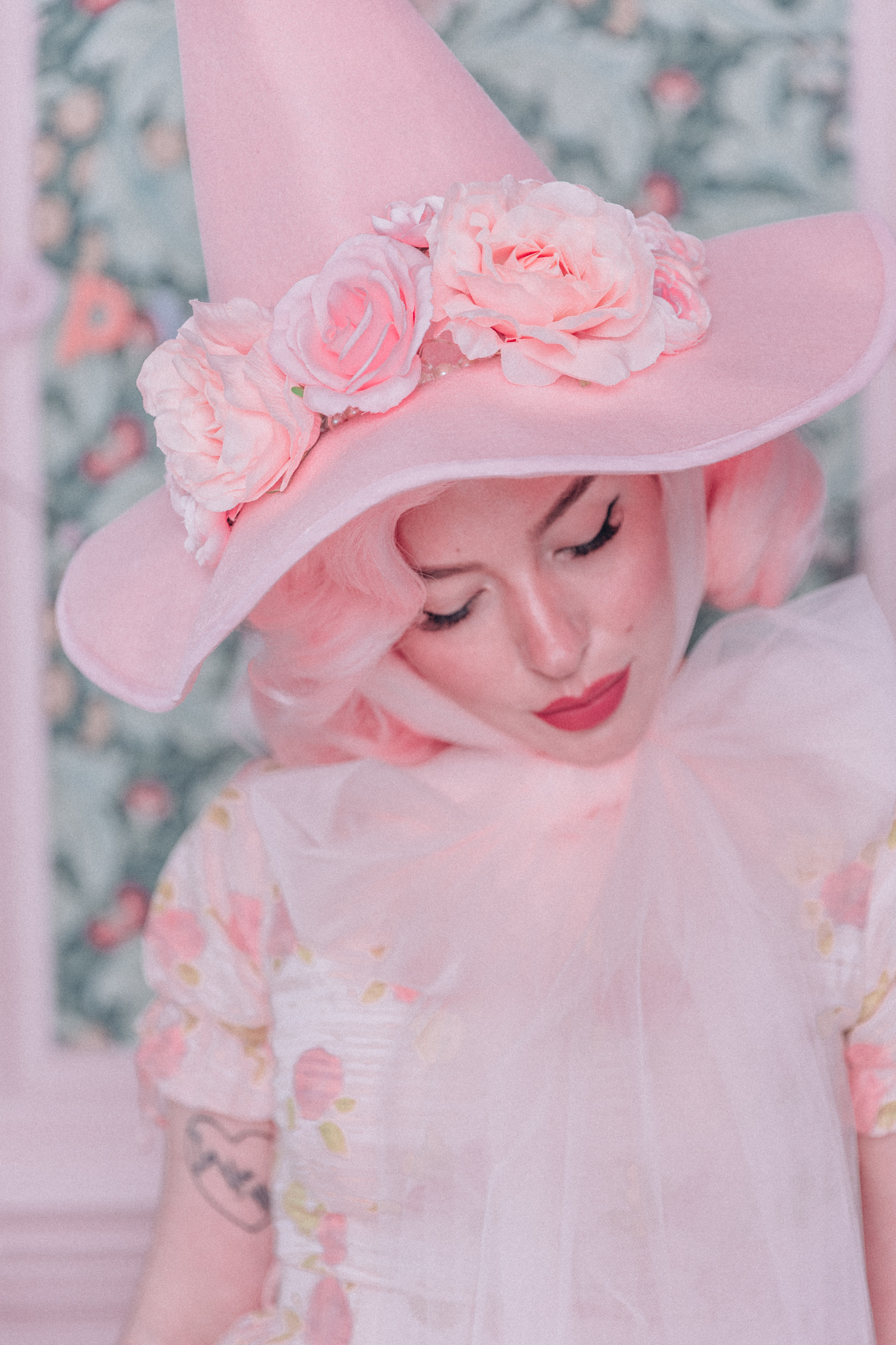 Woman wearing a pink witch hat with flowers and tulle ties